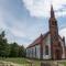 Eine typische KIrche aus Backsteinen und Naturmauerwerk, weiss verputzt, wobei die Natursteine zum teilfrei liegen..